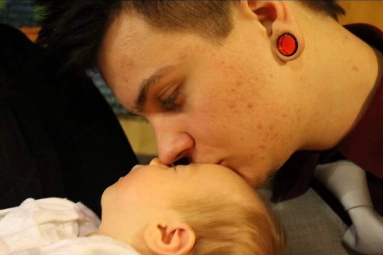 Joel kissing his child's forehead